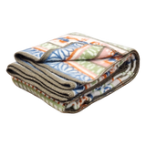 Folded lambswool blanket featuring a geometric and leaf pattern in green, orange, blue, and beige with gray trim along the edges.