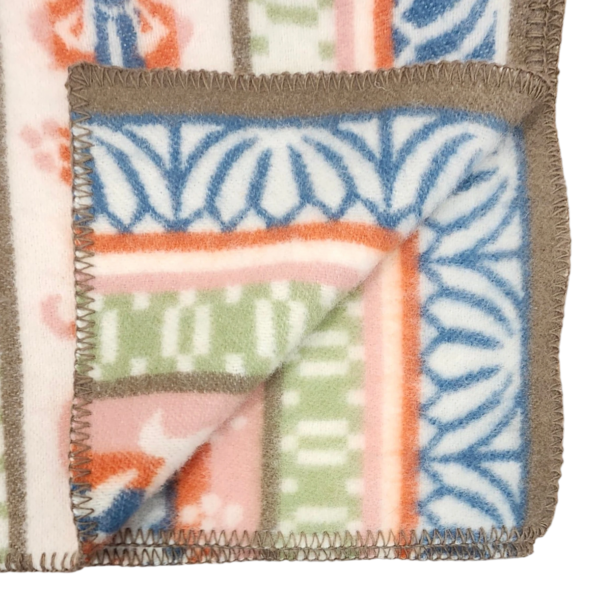 Close-up of a lambswool blanket showing geometric and floral Swedish folk art patterns in blue, green, pink, and orange sections.
