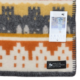 A Swedish blanket made from Norwegian lamb’s wool, featuring orange, yellow, and gray geometric patterns, a black Kerstin Landström Design label, and a product tag underneath.