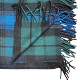 Folded blanket in Black Watch tartan with green, blue, and black stripes, showing fringed edges and one corner turned up.