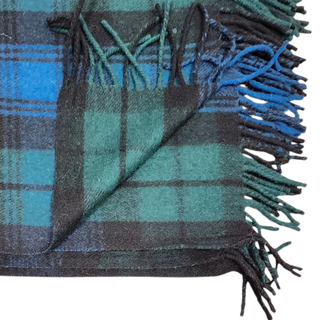 Folded blanket in Black Watch tartan with green, blue, and black stripes, showing fringed edges and one corner turned up.