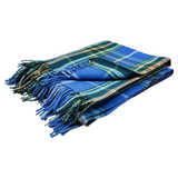 Folded blue and green Scottish tartan blanket with fringed edges on a white background.