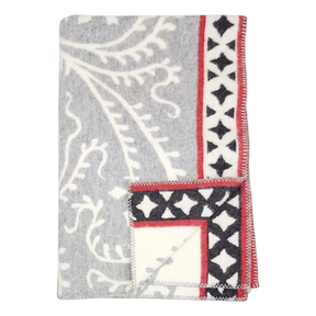 Folded gray fleece blanket with white leaf patterns and a red border featuring black diamond shapes, displayed on a plain white background.