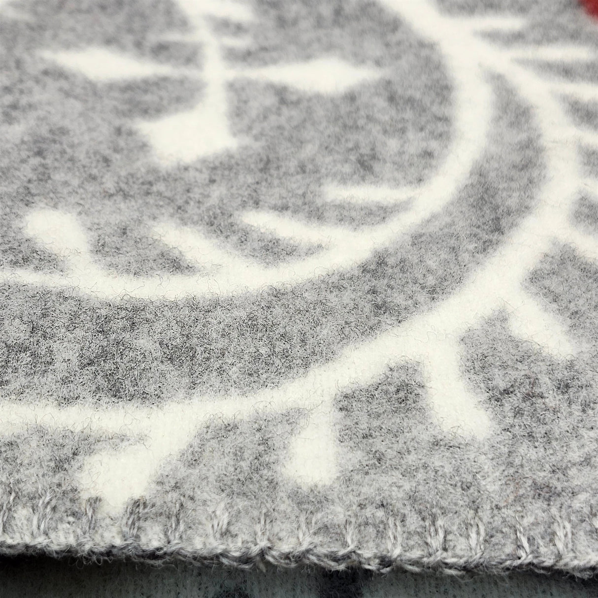 Close-up of a Swedish wool blanket in gray and white with a geometric pattern and visible edge stitching.