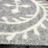 Close-up of a Swedish wool blanket in gray and white with a geometric pattern and visible edge stitching.
