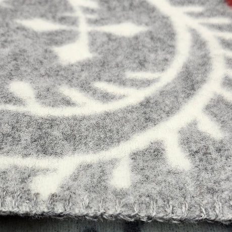 Close-up of a Swedish wool blanket in gray and white with a geometric pattern and visible edge stitching.