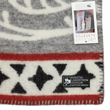 Close-up of a Swedish wool blanket featuring black stars, red and gray stripes, a stitched edge, and two labels, one marked Kerstin Landström Design.