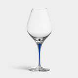 An Orrefors: Intermezzo Blue Aroma Glass 20oz features a clear bowl and blue-tinted crystal stem, elegantly displayed against a gray background.