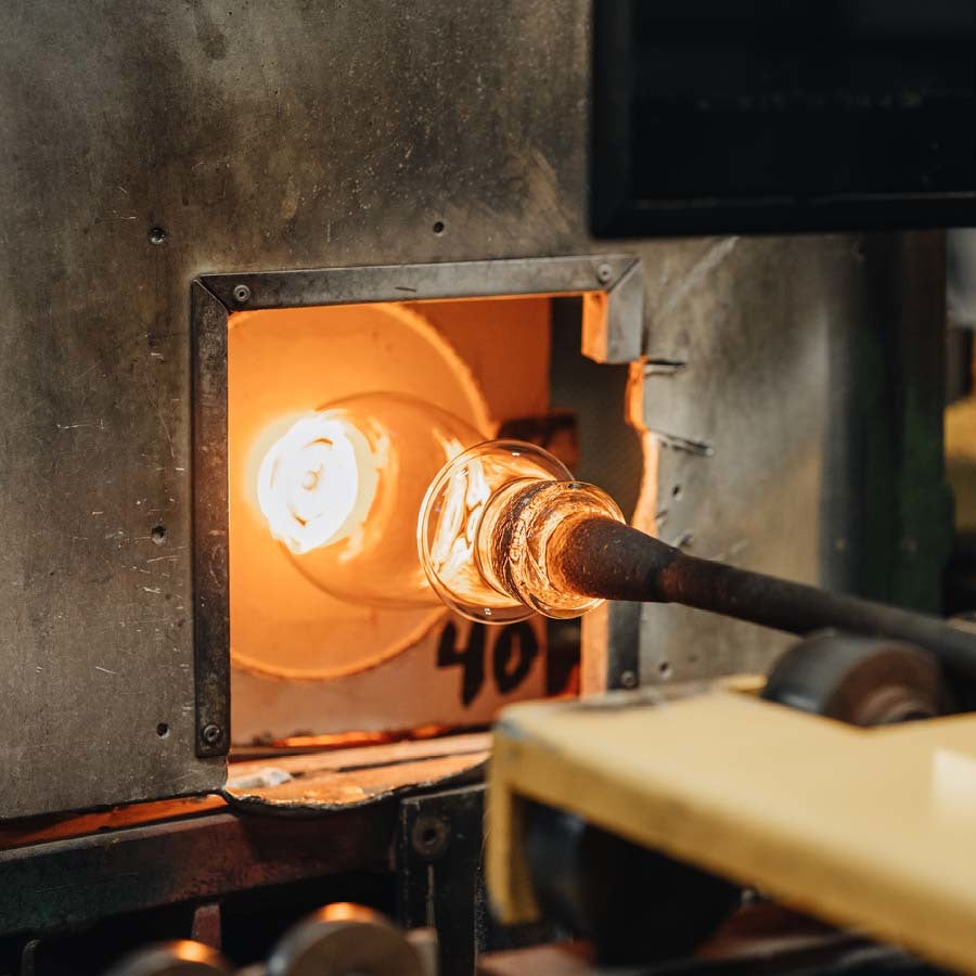 In the bustling glassblowing workshop, molten glass swirls on a blowpipe inside a roaring furnace as artisans craft pieces inspired by the elegance of Orrefors Intermezzo Blue Iced Beverage Glass 15oz, designed by Erika Lagerbielke.