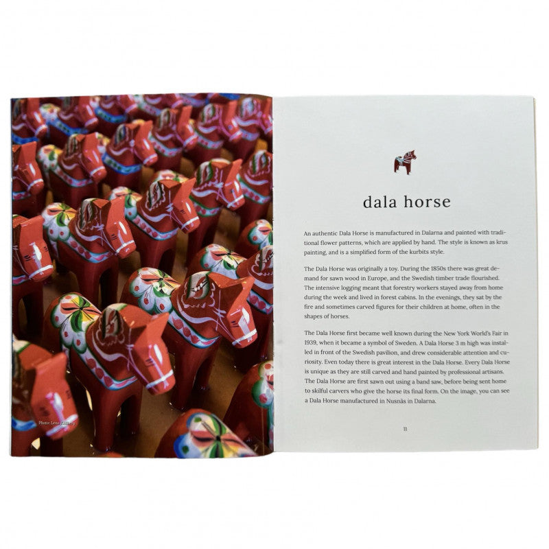 Rows of red Dala horse figurines with decorative patterns stand proudly beside a page from "15 Swedish Icons Stories & Treasures," capturing the essence of Swedish traditions and evoking the charm of an illustrated book.