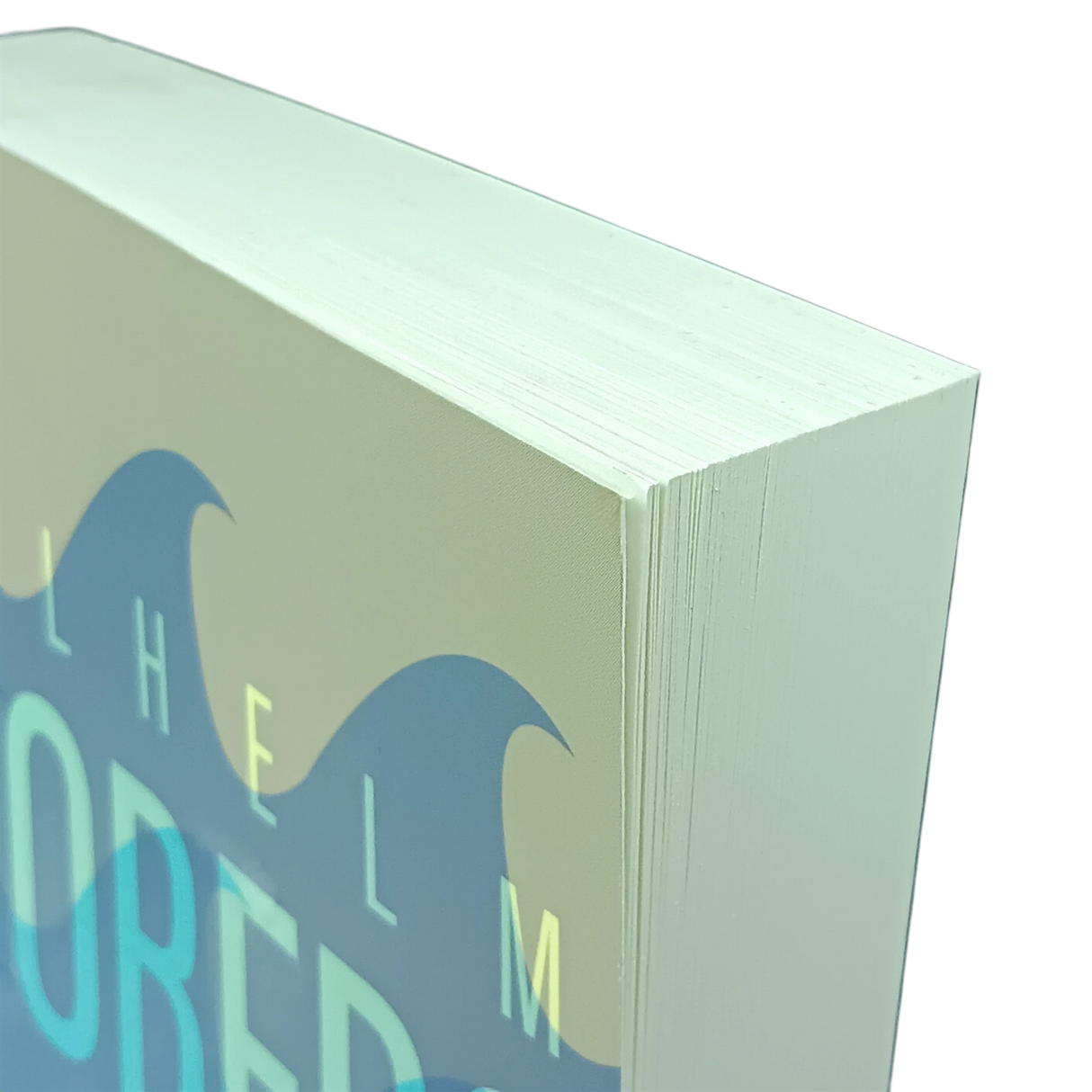 Close-up of the top corner of a thick paperback book with blue wave design and partial visible text on a light background.