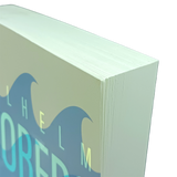 Close-up of the top corner of a thick paperback book with blue wave design and partial visible text on a light background.