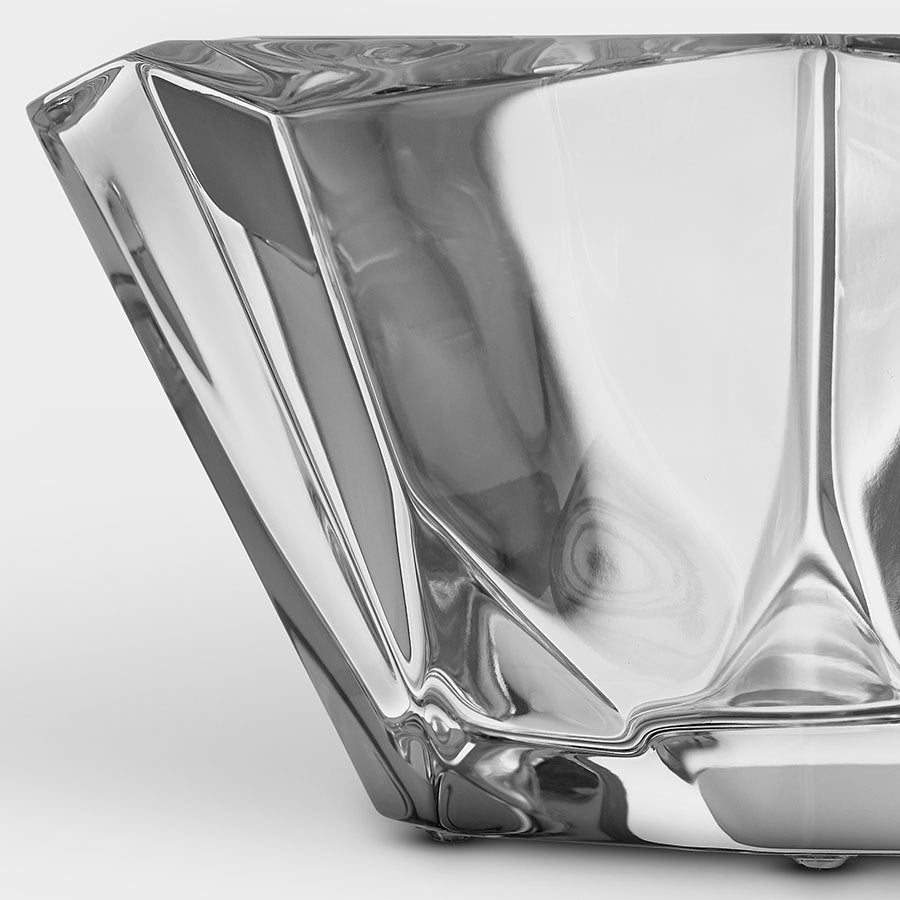 Close-up of an abstract, angular glass sculpture with smooth and reflective surfaces, reminiscent of an Orrefors: Precious Bowl, showcasing a geometric design.