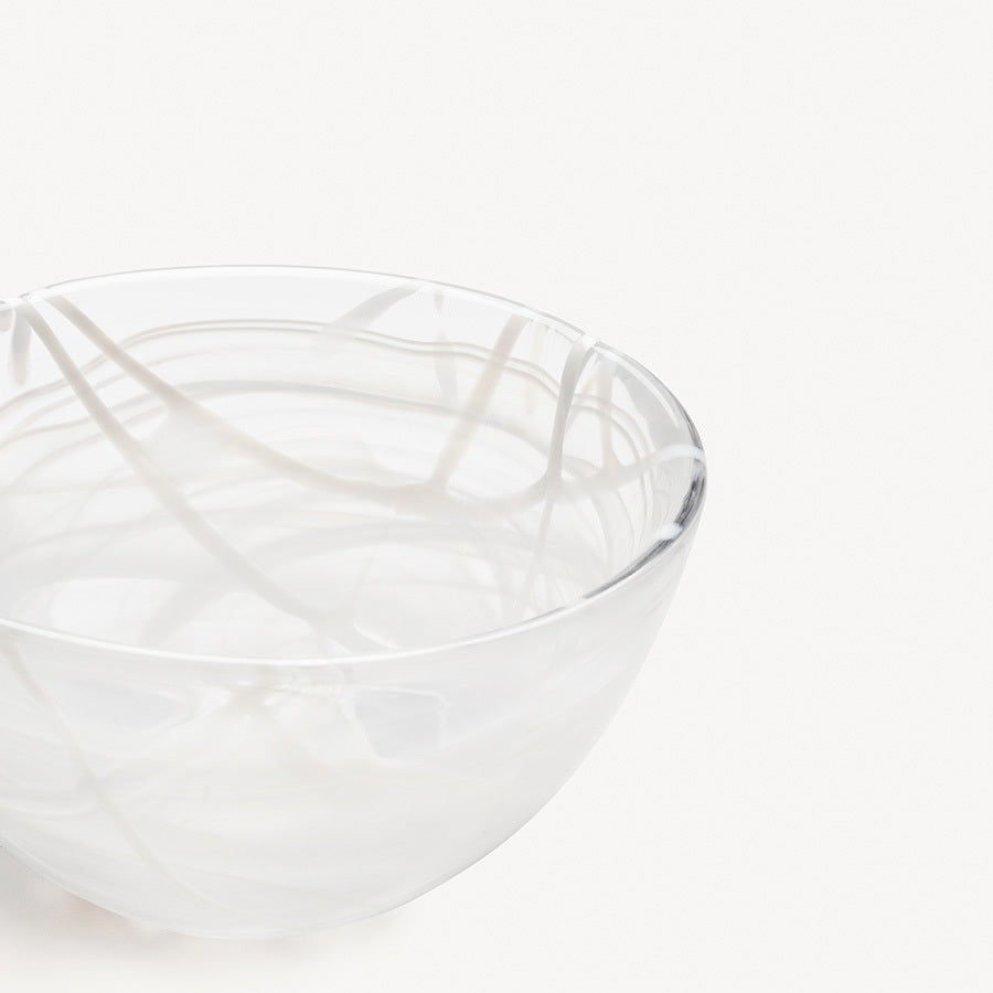 The KostaBoda: Contrast Bowl White, designed by Anna Ehrner, boasts a stunning clear glass with a graceful white swirl that elegantly contrasts against light backgrounds.