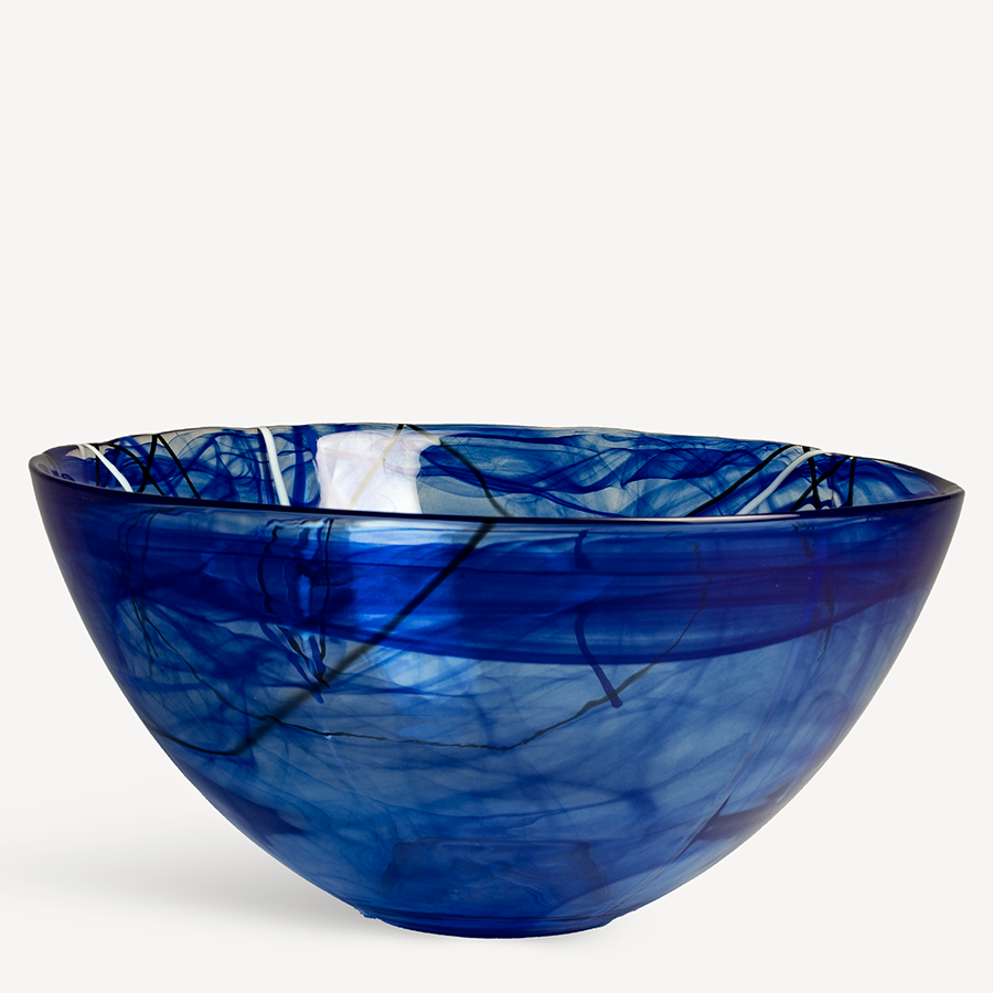 The large KostaBoda Contrast Blue Bowl, designed by Anna Ehrner, features swirling patterns in translucent blue glass that contrast strikingly against a plain white background.