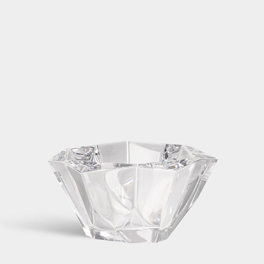 The Orrefors: Precious Bowl, a clear faceted glass masterpiece with a stunning hexagonal design, serves as an elegant crystal centerpiece on any table, adding intricate detailing and timeless appeal to your decor.