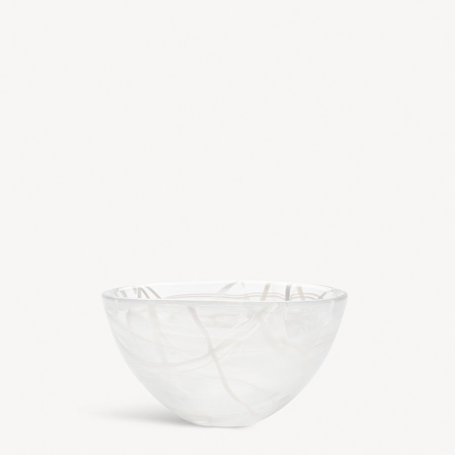 The KostaBoda: Contrast Bowl White, designed by Anna Ehrner, is a clear glass bowl with a delicate swirling white pattern that elegantly stands out against its plain backdrop.