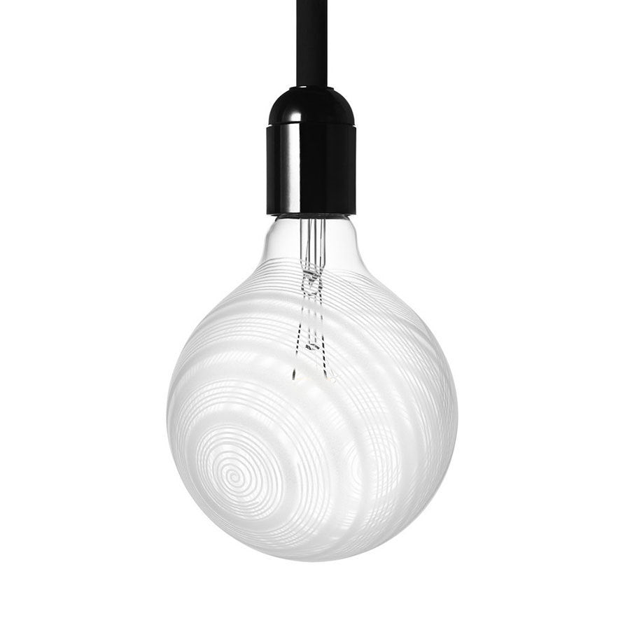 The Orrefors Light Shadow Bulb Loop 25W features a minimalist design with a clear glass bulb and black socket, casting delicate spiral shadows while suspended like a pendulum lamp.