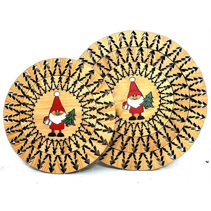 These delightful wooden trivets, named "Trivet: Santa with gift & tree Natural Laser Cut with Christmas Trees," showcase a Santa holding a tree and gift, framed by a radial black tree pattern. Handmade in Estonia, they add an authentic charm to your holiday decor.