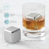 A glass of whiskey with a large Cubes: Stainless Steel Ice Cube (1.57" square) inside; another sits beside it. Text highlights features like reusable ice cubes, fast freeze time, and the set of 2 in a plastic case.