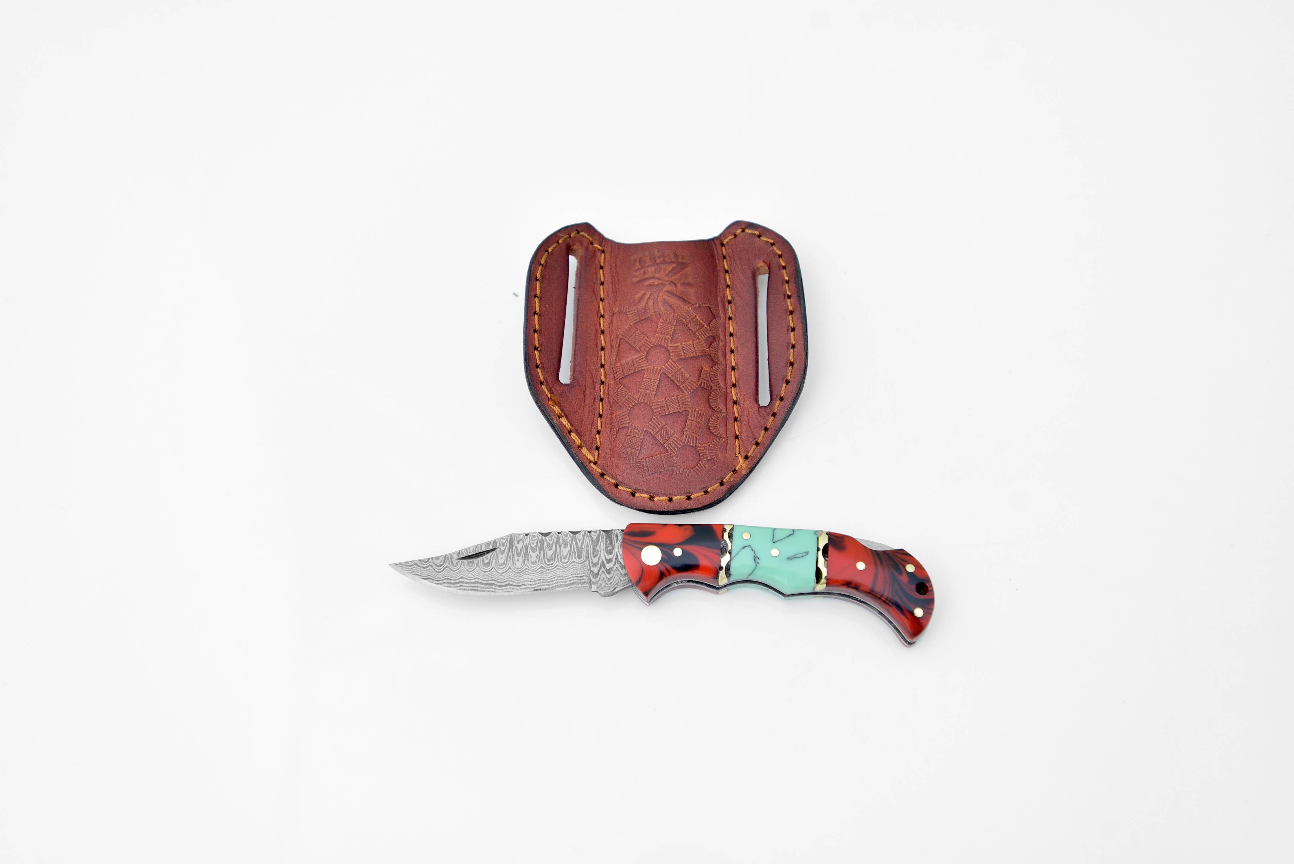The Knife: Damascus steel pocket folding knife with a Red & Acqua handle is shown beside its brown leather sheath on a white background.