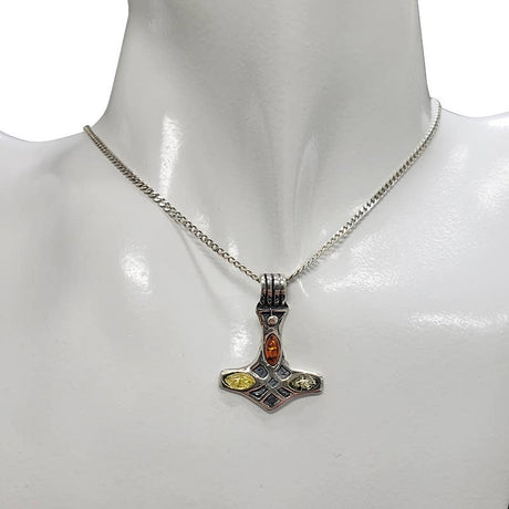 A sterling silver chain necklace with a 1" x 0.75" Multi-Color Baltic Amber Thor's Hammer pendant, shown on a mannequin bust.