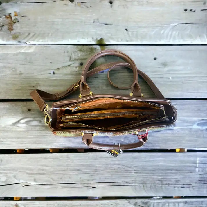 The Bag: Harris Tweed Double Handle Tote - Dark Brown, featuring gold hardware and visible compartments with a zipper, is shown from above on a weathered wooden surface.