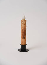 LED taper candle with a Santa Claus illustration in a black metal holder.