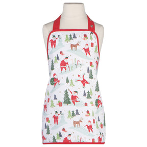 A mannequin displays the "Kids Apron - Must Be Santa," a festive white baking apron with red straps, decorated with Christmas-themed illustrations of Santa Claus, reindeer, gifts, trees, and candy canes.