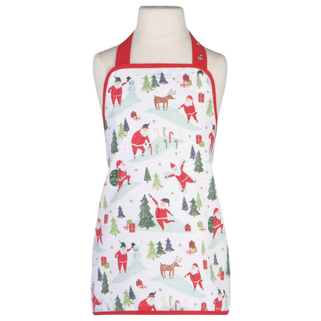 A mannequin displays the "Kids Apron - Must Be Santa," a festive white baking apron with red straps, decorated with Christmas-themed illustrations of Santa Claus, reindeer, gifts, trees, and candy canes.