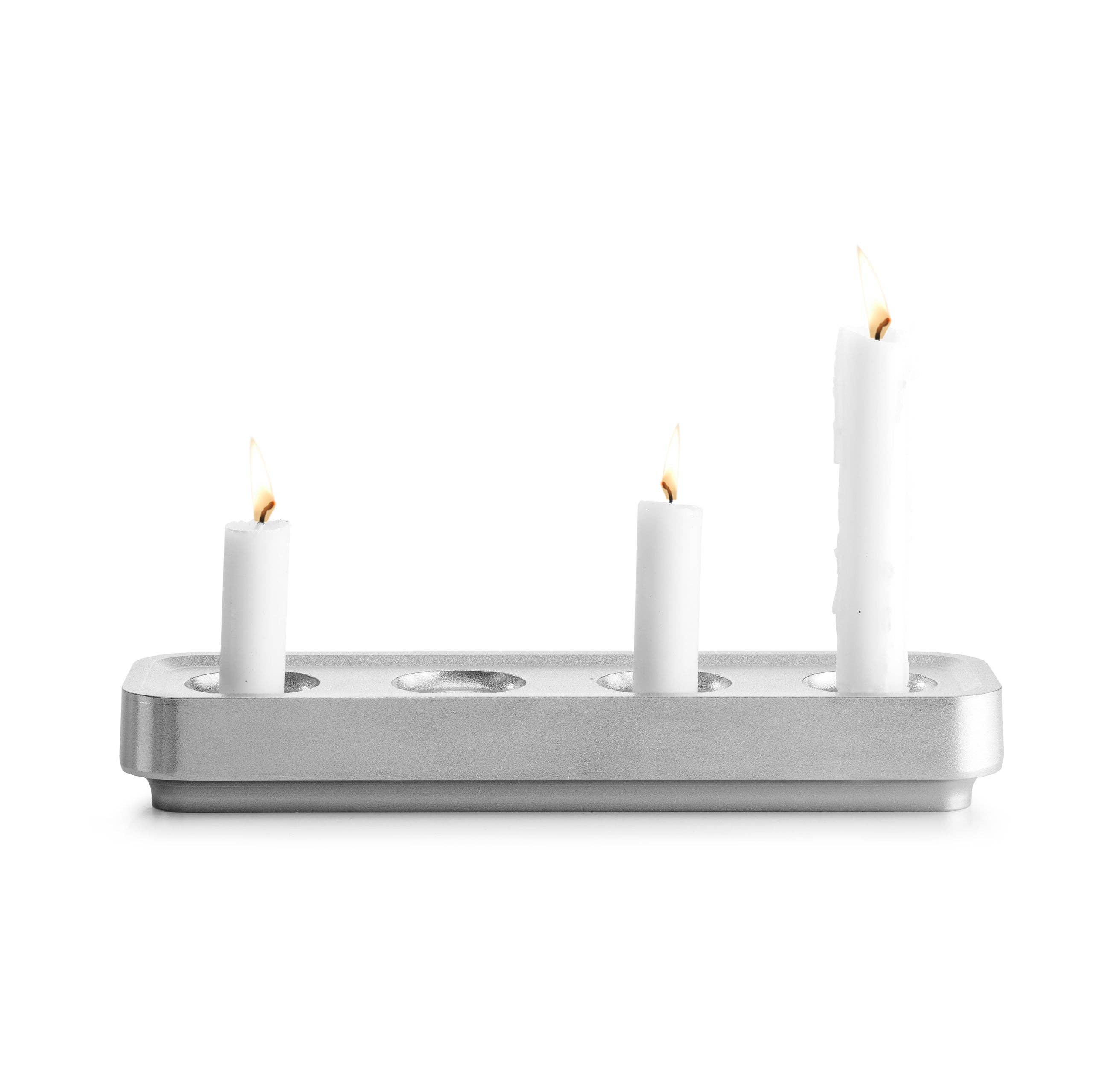 Three lit white candles of varying heights in a sleek, rectangular Stumpastaken White Powdercoated Swedish Candle Holder, crafted from recycled aluminum and inspired by Swedish design.