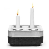 The Stumpastaken Fyran Four Candle Holder - Square, made from 100% recycled material with a white powder-coated finish, holds candles of varying heights for a stylish, sustainable interior decor accent.