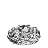 A burning tealight sits in a faceted, crystal-like glass holder set against a white background.