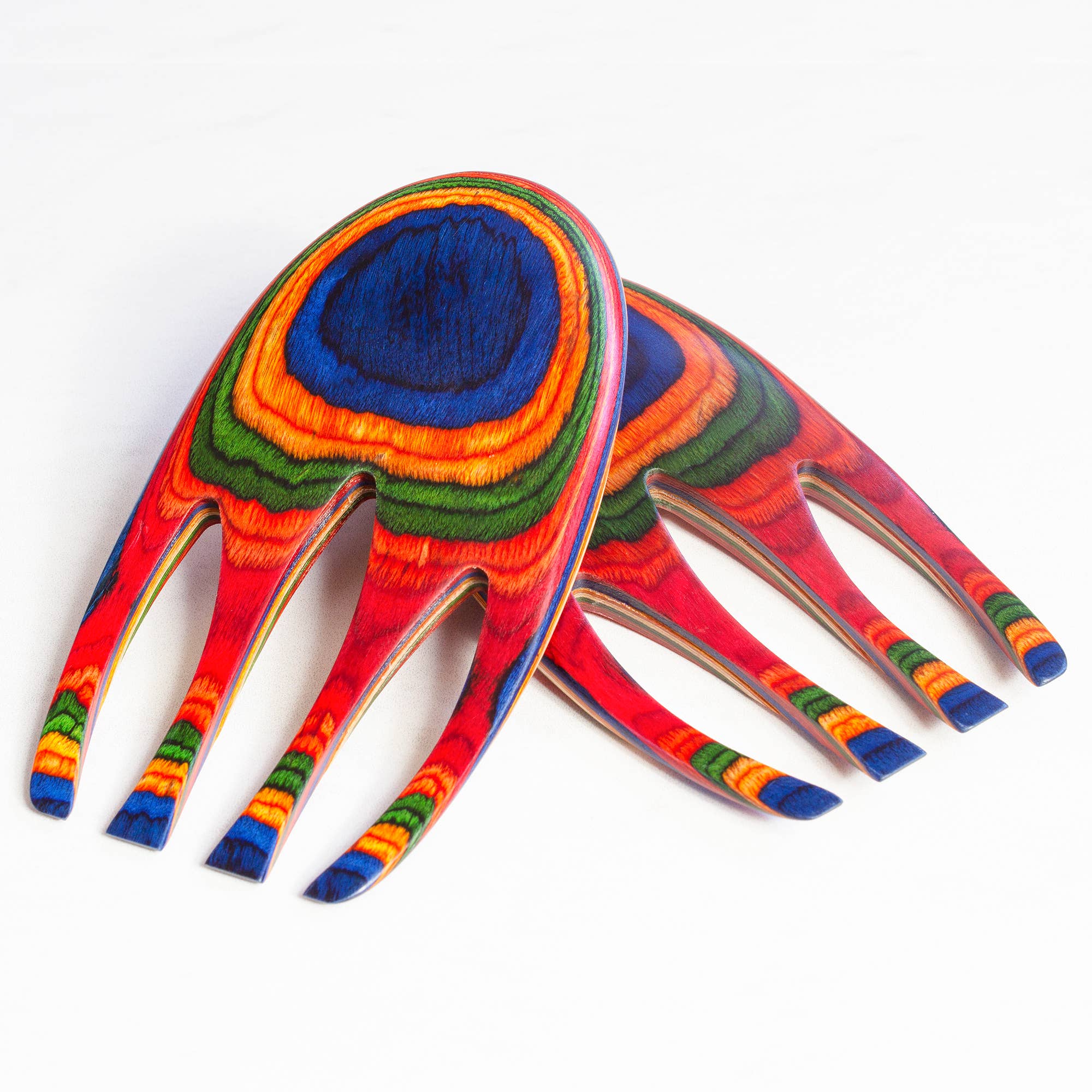 The Marrakesh Salad Hands, a set of two vibrant wooden utensils with four prongs each, showcase striking patterns in red, blue, green, and orange hues. They are ideal as eye-catching decorative pieces or as unique tools for tossing pasta salads.