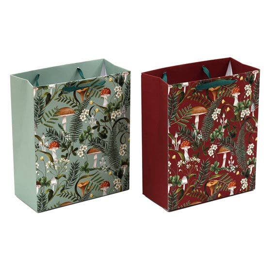 Product Description: Discover the enchanting "Gift Bag: Forest Mushroom Red or Green" (7.5"w x 9"h x 3.5"d), featuring two whimsical gift bags with handles. One comes in green, adorned with charming mushroom and fern designs, while the other is in red, showcasing similar captivating patterns. These bags are perfect for adding a touch of fantasy to your gift wrapping.