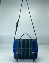 The Bag: Nova Scotia Patsy Handbag is a satchel-style accessory with blue, green, and red Provincial tartan fabric on the front, blue leather trim, adjustable shoulder strap, top handle, and buckle closures.