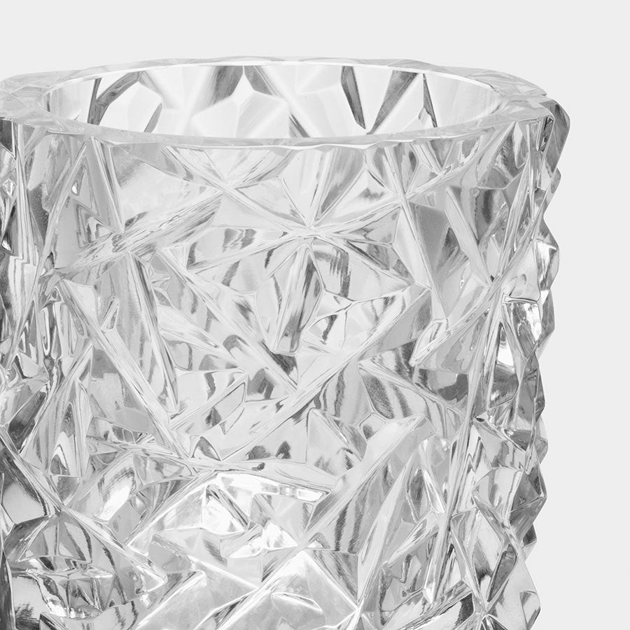 Close-up of a clear, textured glass vase with a geometric, faceted surface reminiscent of the Orrefors: Carat Candle Holder Medium, set against a plain, light background.