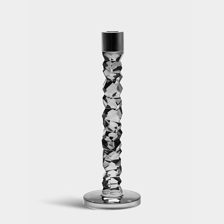 The Orrefors: Carat Graphite Candlestick Large by Lena Bergström boasts a faceted glass design with a textured column and round base, elegantly displayed on a plain background.