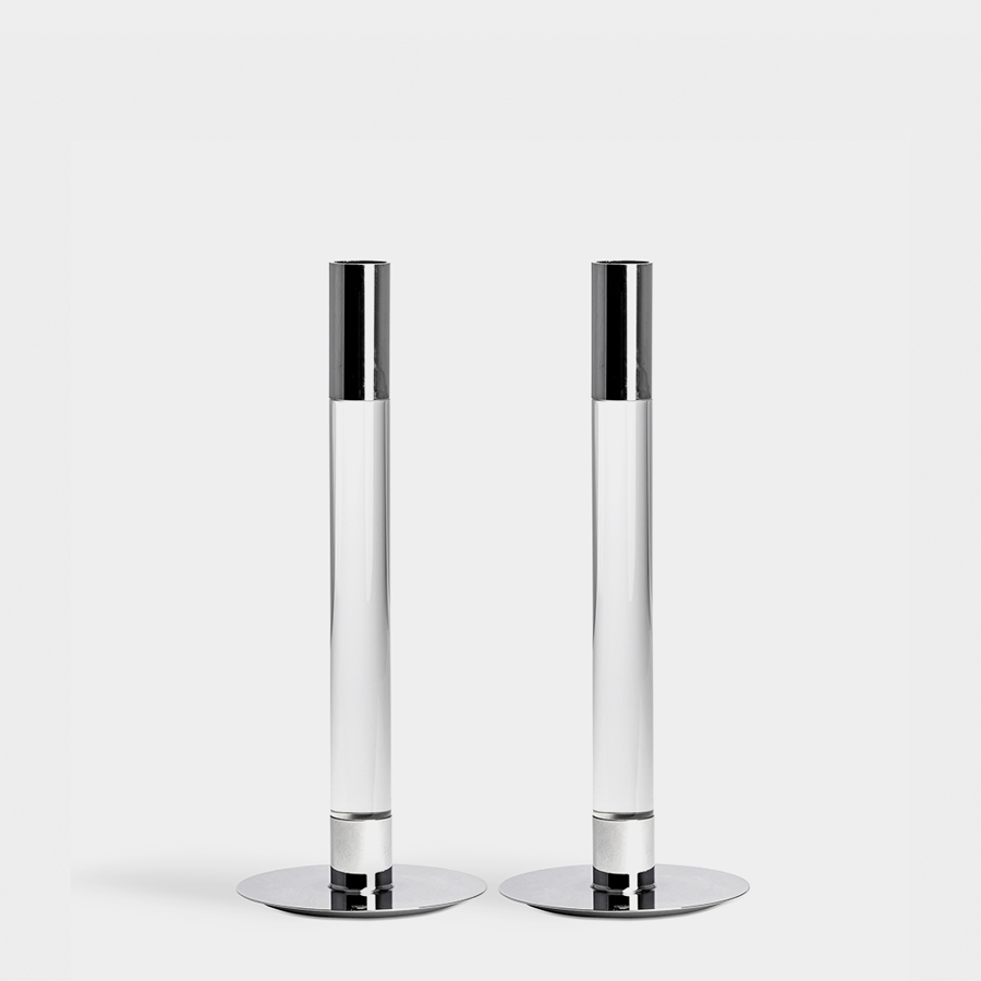 The Orrefors Lumiere Candlestick Silver Medium set of 2 features two transparent cylindrical holders with shiny silver bases and tops, evoking Ingegerd Råmans elegant style, beautifully showcased against a white background.