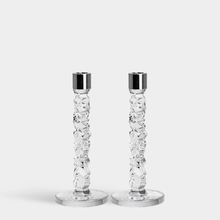 A pair of Orrefors: Carat Candlestick Silver Medium features two clear faceted crystal glass candlesticks with glossy silver tops against a white background, showcasing Lena Bergströms exquisite craftsmanship.