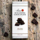 An Icelandic dark chocolate bar on a wooden surface, with several pieces of 70% dark chocolate arranged nearby.