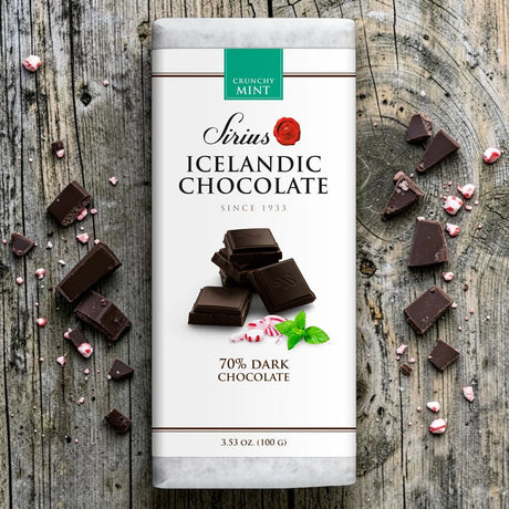 A mint chocolate bar labeled 70% cocoa, with pieces of broken chocolate and crushed candy scattered on a rustic wooden surface.