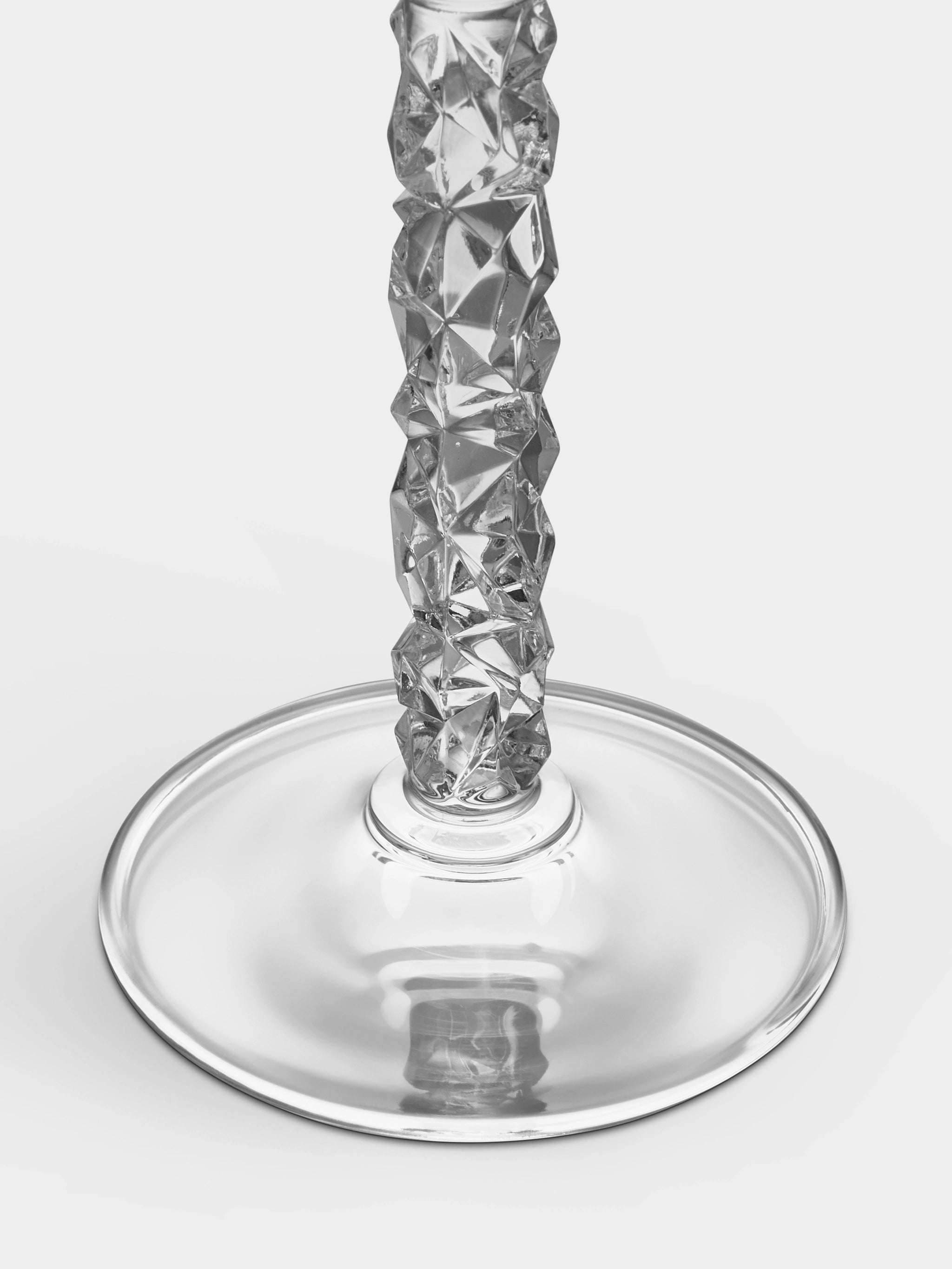 A close-up of a crystal champagne flute stem from the Orrefors Carat Collection, showcasing a textured, faceted design and a smooth base on a white background.