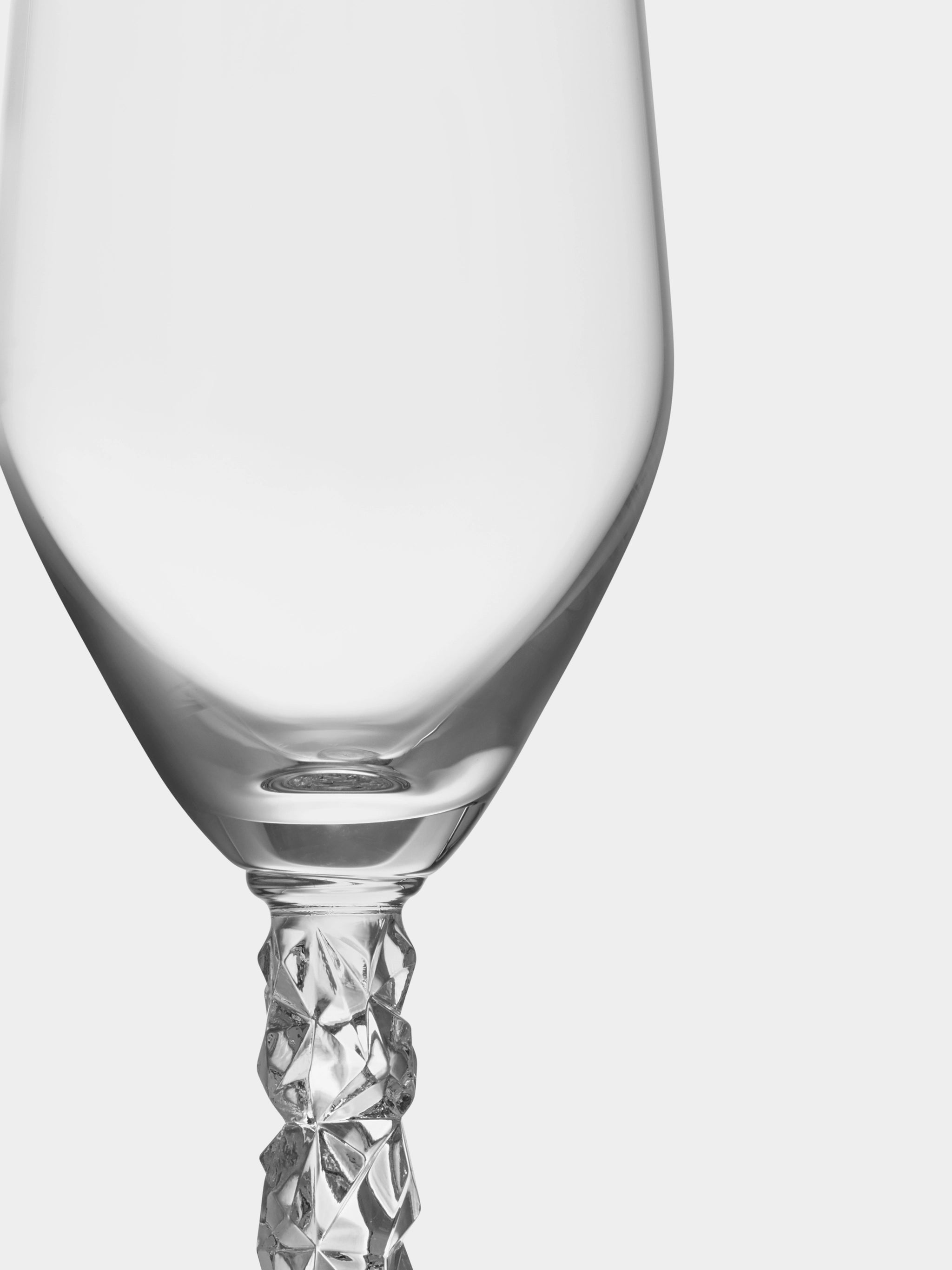 Close-up of an elegant crystal champagne flute with a textured stem from the Orrefors Carat Collection, set against a plain background.