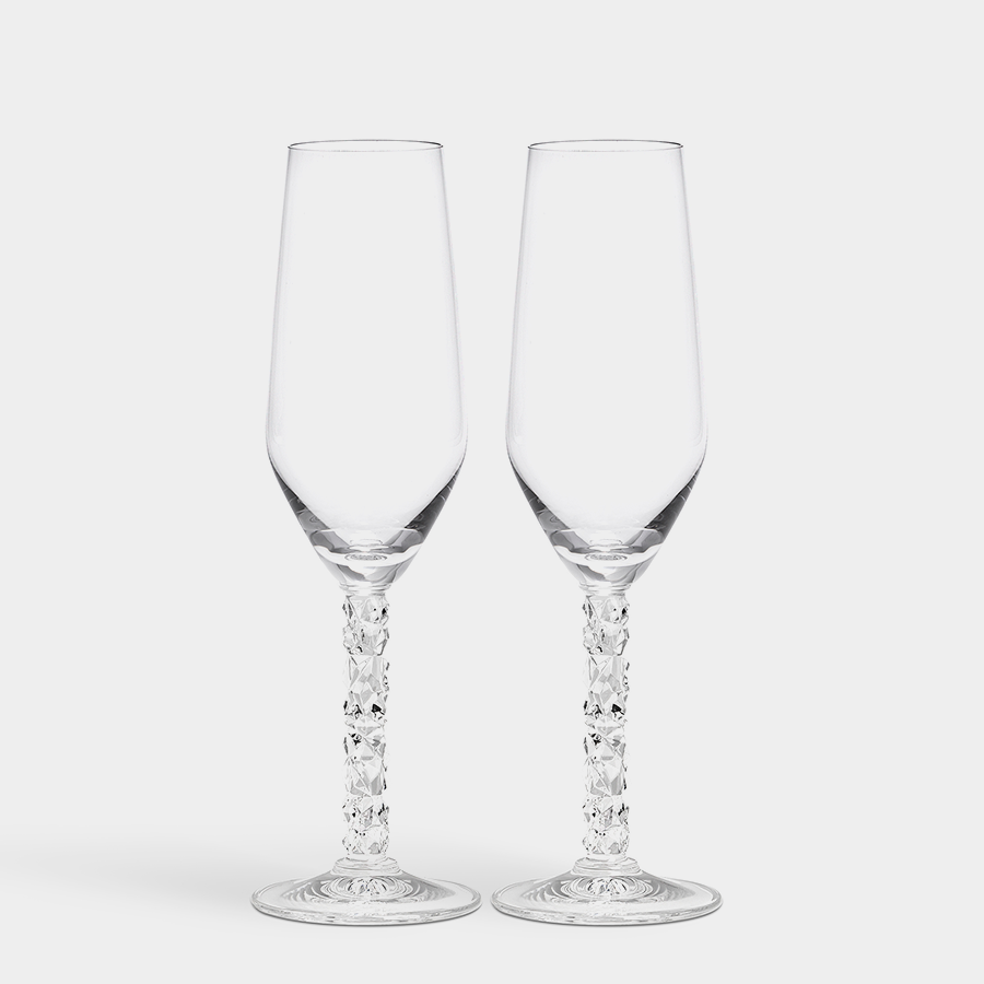 Two elegant Orrefors Carat Champagne Flutes, each 8oz with decorative stems, sit gracefully against a plain white backdrop, epitomizing the sophistication of the Carat Collection.