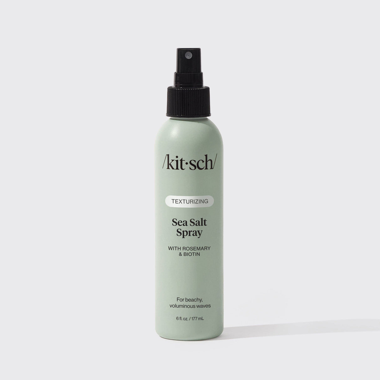 A green 6 fl oz bottle of KITSCH Spray: Texturizing Sea Salt Hair Spray with Rosemary & Biotin is displayed against a plain white background. This vegan hair product features clean ingredients and serves as both a volumizing spray and texturizer, making it ideal for creating effortless, beachy waves.