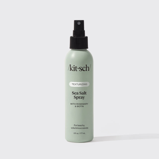 A green 6 fl oz bottle of KITSCH Spray: Texturizing Sea Salt Hair Spray with Rosemary & Biotin is displayed against a plain white background. This vegan hair product features clean ingredients and serves as both a volumizing spray and texturizer, making it ideal for creating effortless, beachy waves.