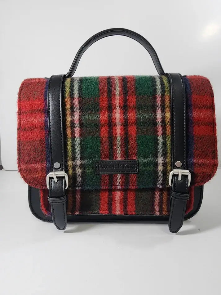 The Bag: Royal Stewart Handbag is a satchel-style bag with a red, green, black, and white Scottish tartan wool flap, black leather trim, top handle, and two front buckles.