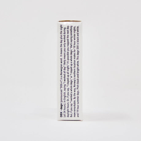 The side view of the DEK Døgn (Norway) playing card box displays text in blue. The predominantly white, rectangular box captures a distinctive aesthetic influenced by Norwegian design.