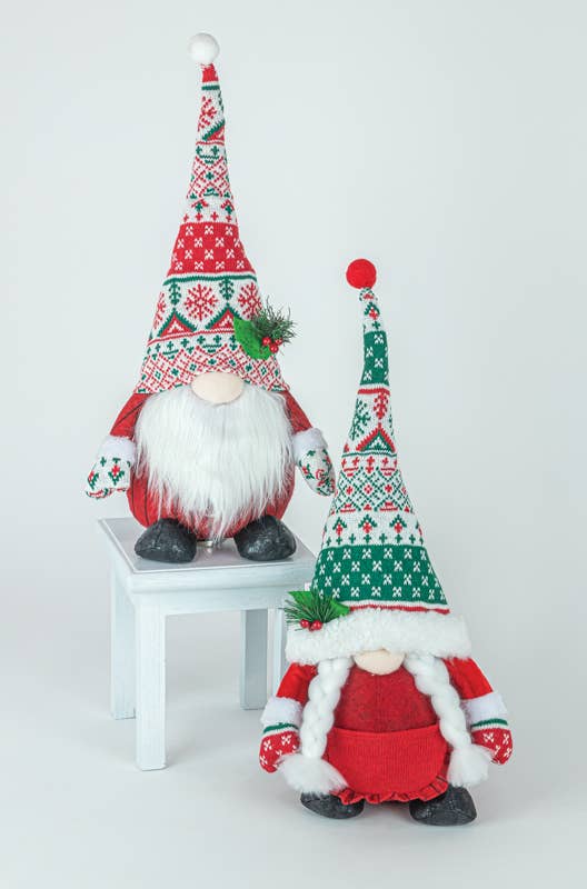 Two WINTER KISSES GNOME SITTER plushies, featuring long white beards, perch on a white stool. They are dressed in red and green knit hats and matching outfits, ideal for decorative use.